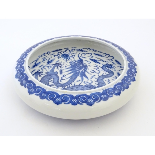 47 - A Chinese blue and white bowl / dish decorated with a dragon and flaming pearl amongst stylised clou... 