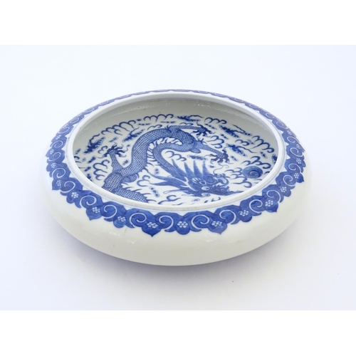 47 - A Chinese blue and white bowl / dish decorated with a dragon and flaming pearl amongst stylised clou... 