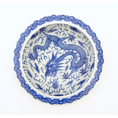 47 - A Chinese blue and white bowl / dish decorated with a dragon and flaming pearl amongst stylised clou... 