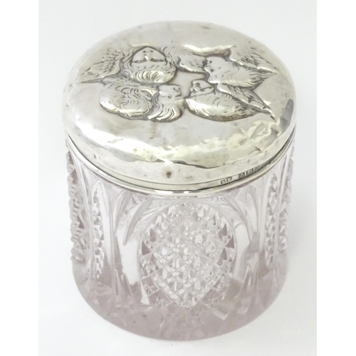 240 - A cut glass dressing table jar with silver top with embossed angel detail, hallmarked Birmingham 190... 