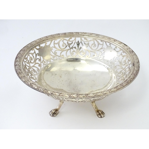 244 - A large silver bon bon dish / fruit dish with pierced scroll detail, standing on four lion paw feet,... 