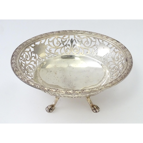 244 - A large silver bon bon dish / fruit dish with pierced scroll detail, standing on four lion paw feet,... 