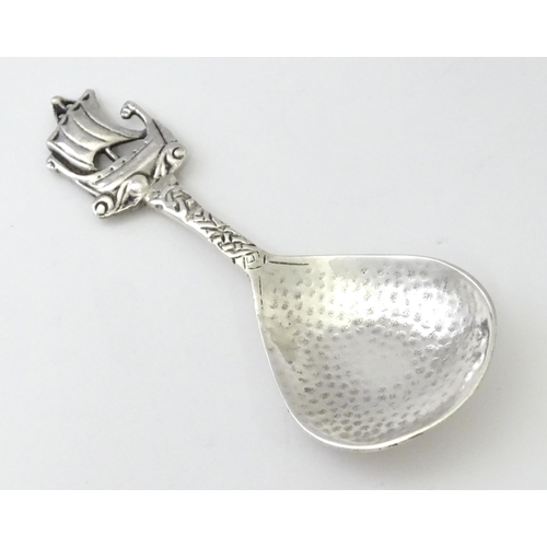 268 - A silver caddy spoon with hammered decoration and Ionia style boat finial and Celtic detail to handl... 