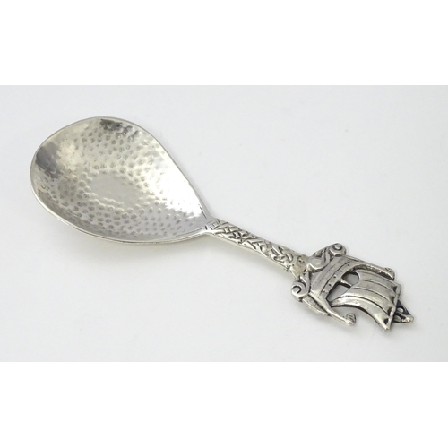 268 - A silver caddy spoon with hammered decoration and Ionia style boat finial and Celtic detail to handl... 