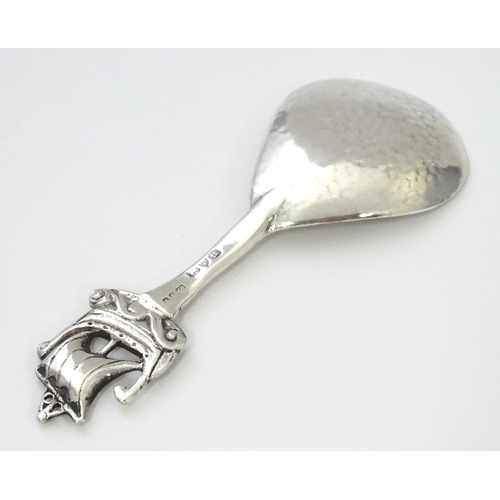 268 - A silver caddy spoon with hammered decoration and Ionia style boat finial and Celtic detail to handl... 