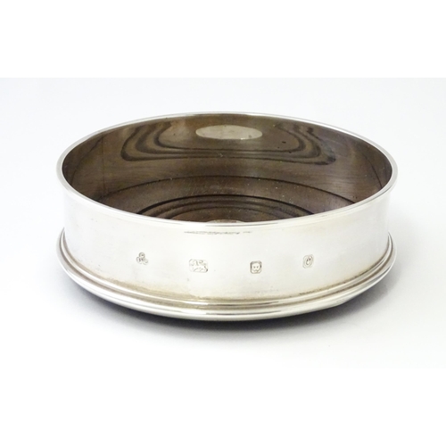 273 - A silver bottle coaster with turned wooden base, hallmarked London 1988, maker C S R Ltd . Approx. 5... 