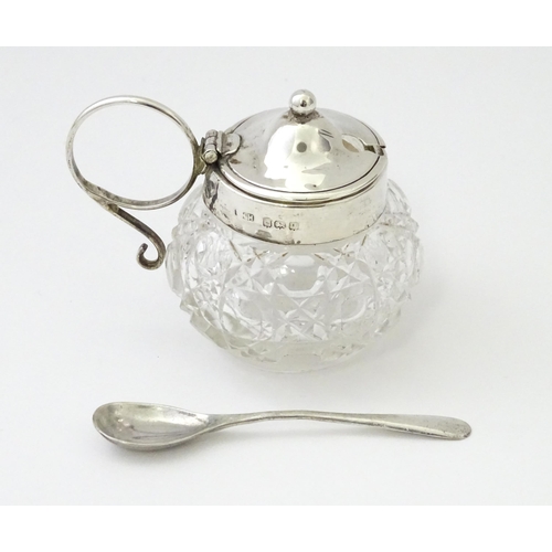 350 - A cut glass mustard pot with silver mounts and handle together with a silver mustard spoon. Both hal... 