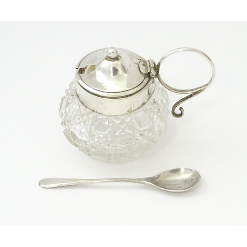 350 - A cut glass mustard pot with silver mounts and handle together with a silver mustard spoon. Both hal... 