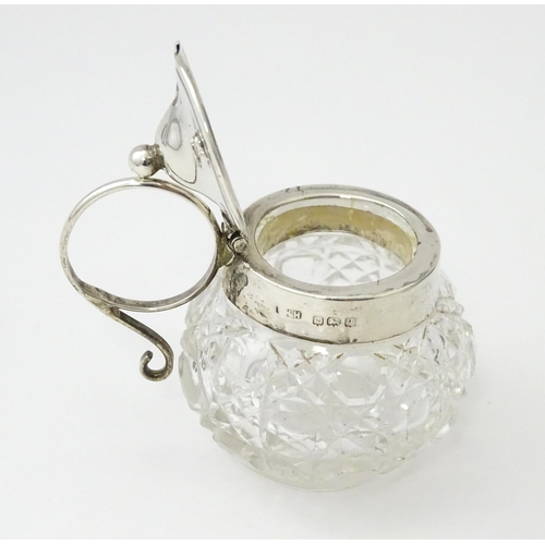 350 - A cut glass mustard pot with silver mounts and handle together with a silver mustard spoon. Both hal... 