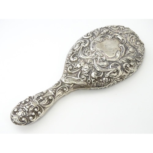 371 - A Victorian silver hand mirror with embossed foliate and mask decoration, hallmarked Chester 1899, m... 