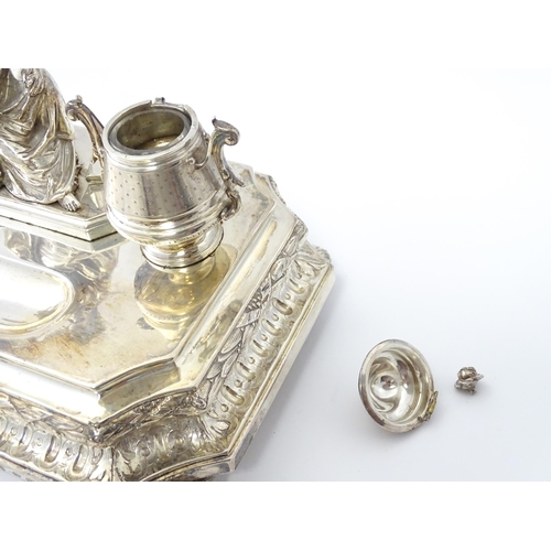 454 - A silver desk standish with Classical muse flanked by two urn formed inkwells and recessed pen well,... 