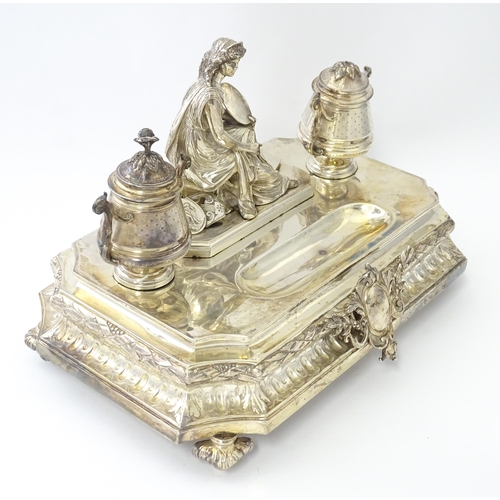 454 - A silver desk standish with Classical muse flanked by two urn formed inkwells and recessed pen well,... 