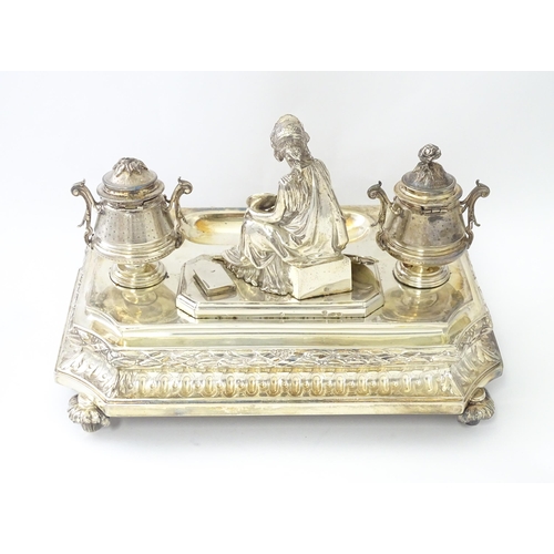 454 - A silver desk standish with Classical muse flanked by two urn formed inkwells and recessed pen well,... 