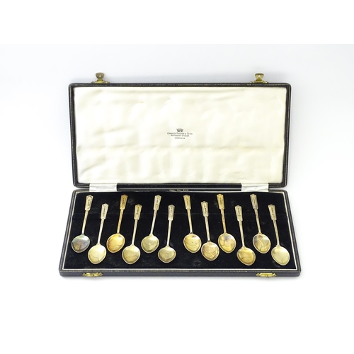 488 - A cased set of twelve silver gilt teaspoons with black enamel detail to reverse of handles and bowls... 