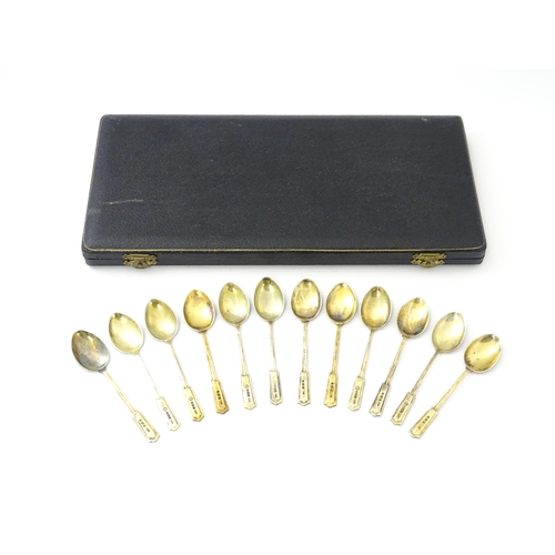 488 - A cased set of twelve silver gilt teaspoons with black enamel detail to reverse of handles and bowls... 