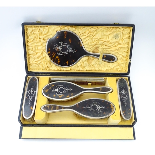 494 - A cased silver and tortoiseshell dressing table set with pique work detail comprising hand mirror an... 