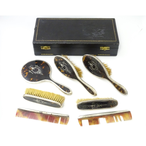 494 - A cased silver and tortoiseshell dressing table set with pique work detail comprising hand mirror an... 