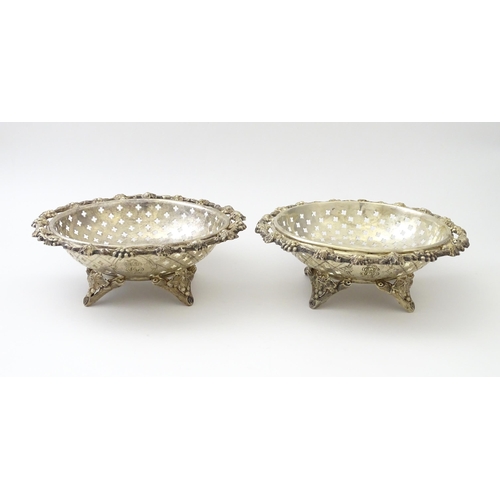 516 - A pair of silver plate dishes of circular form with pierced quatreform detail and fruiting vine deco... 