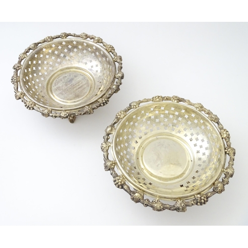 516 - A pair of silver plate dishes of circular form with pierced quatreform detail and fruiting vine deco... 