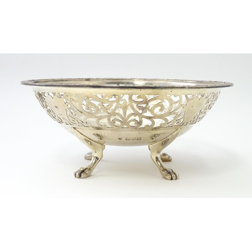 463 - A large silver bon bon dish / fruit dish with pierced scroll detail, standing on four lion paw feet,... 