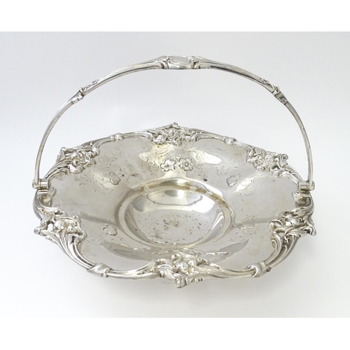 467 - A Victorian silver cake basket with floral and acanthus detail, a swing handle and later inscription... 