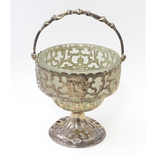 468 - A Victorian silver sugar basket of pedestal form with pierced decoration, swing handle and glass lin... 