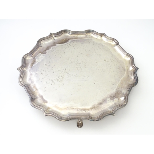 473 - A silver salver with engraved inscription to centre, standing on four out swept feet, hallmarked Lon... 