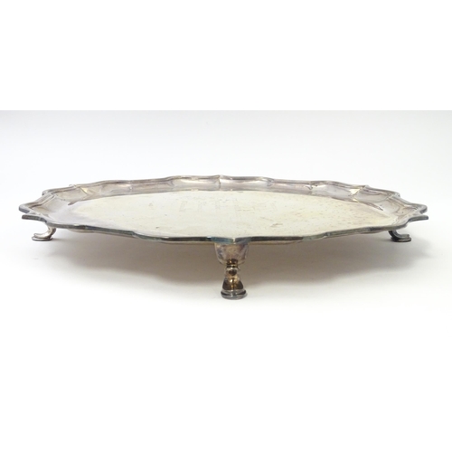 473 - A silver salver with engraved inscription to centre, standing on four out swept feet, hallmarked Lon... 