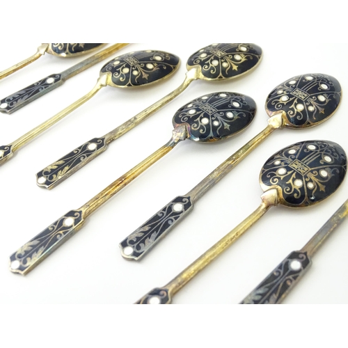 488 - A cased set of twelve silver gilt teaspoons with black enamel detail to reverse of handles and bowls... 