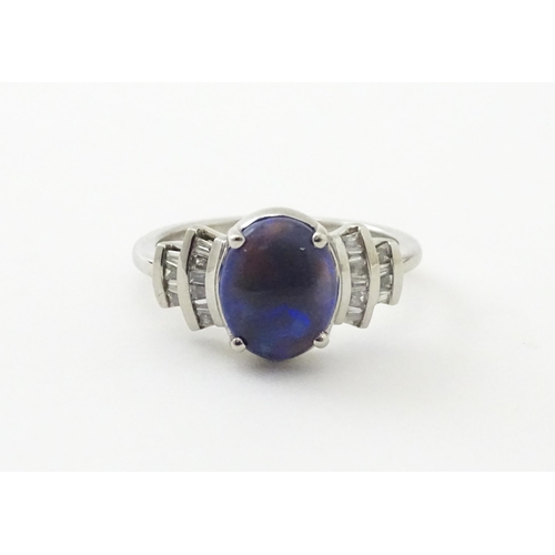 570 - A platinum ring set with central black opal cabochon flanked by diamonds in an Art deco style settin... 