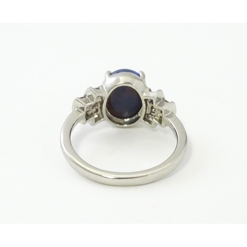 570 - A platinum ring set with central black opal cabochon flanked by diamonds in an Art deco style settin... 