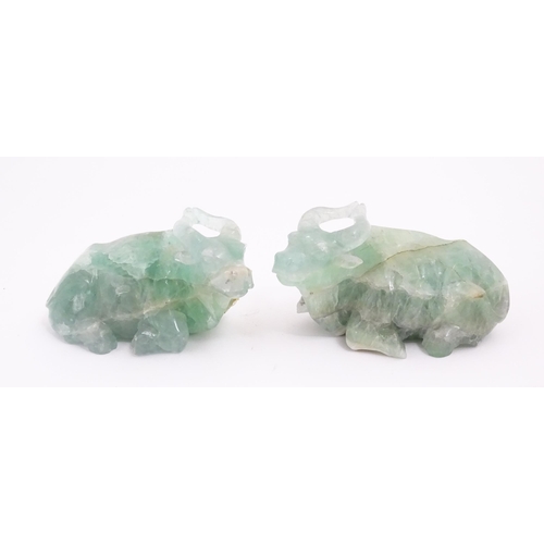 1017 - Two Chinese carved green fluorite models of recumbent buffalo, on wooden stands. Approx. 5