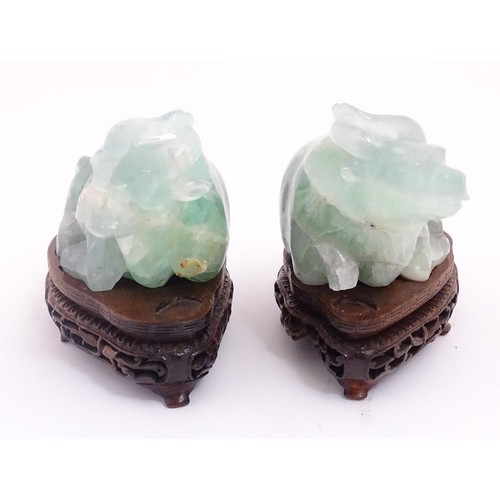 1017 - Two Chinese carved green fluorite models of recumbent buffalo, on wooden stands. Approx. 5