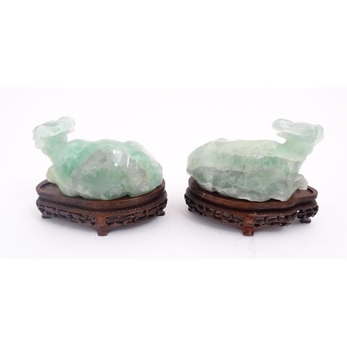 1017 - Two Chinese carved green fluorite models of recumbent buffalo, on wooden stands. Approx. 5