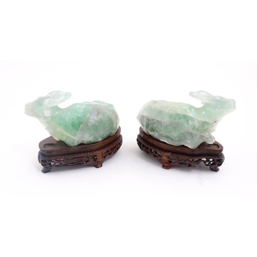 1017 - Two Chinese carved green fluorite models of recumbent buffalo, on wooden stands. Approx. 5