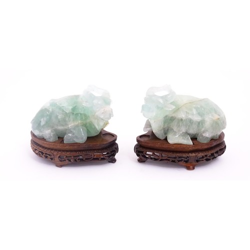 1017 - Two Chinese carved green fluorite models of recumbent buffalo, on wooden stands. Approx. 5