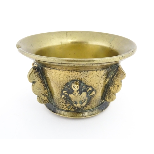 1092 - A small late 17th / early 18thC bronze mortar with mask / cherub head detail. Approx. 2 3/4