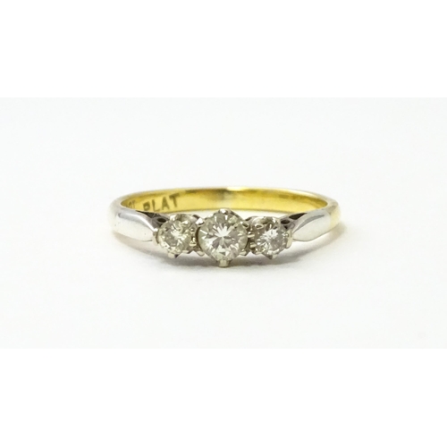 544 - An 18ct gold ring with platinum set trio of diamonds. Ring size approx. L 1/2