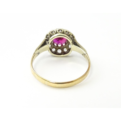 553 - A gold ring set with central red stone flanked by white stones. Ring size approx. O