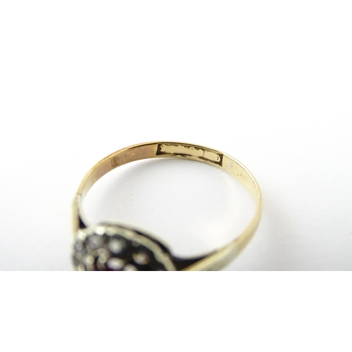 553 - A gold ring set with central red stone flanked by white stones. Ring size approx. O