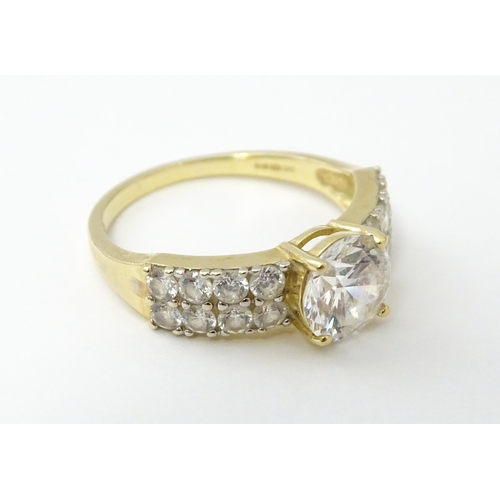 554 - A 14ct gold ring set with central white stone flanked by further white stones. Ring size approx. R 1... 