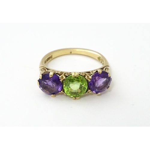 561 - A 9ct gold ring set with purple amethyst and green stone. Ring size approx. O.