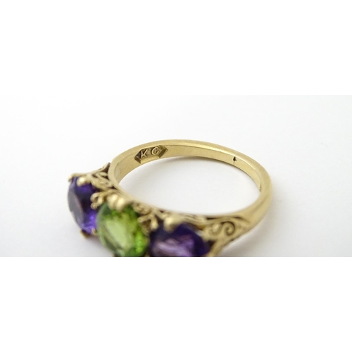 561 - A 9ct gold ring set with purple amethyst and green stone. Ring size approx. O.