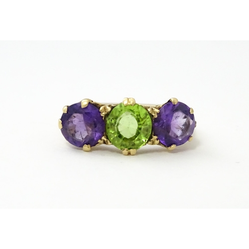 561 - A 9ct gold ring set with purple amethyst and green stone. Ring size approx. O.