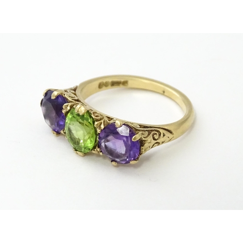 561 - A 9ct gold ring set with purple amethyst and green stone. Ring size approx. O.