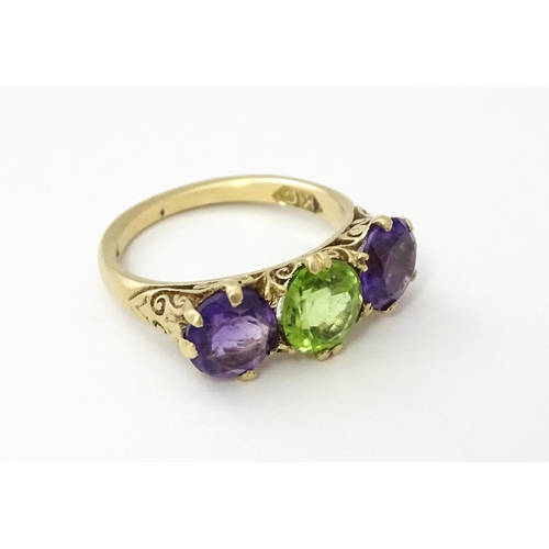 561 - A 9ct gold ring set with purple amethyst and green stone. Ring size approx. O.