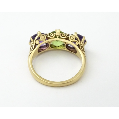 561 - A 9ct gold ring set with purple amethyst and green stone. Ring size approx. O.