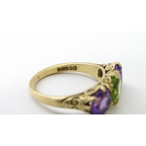 561 - A 9ct gold ring set with purple amethyst and green stone. Ring size approx. O.