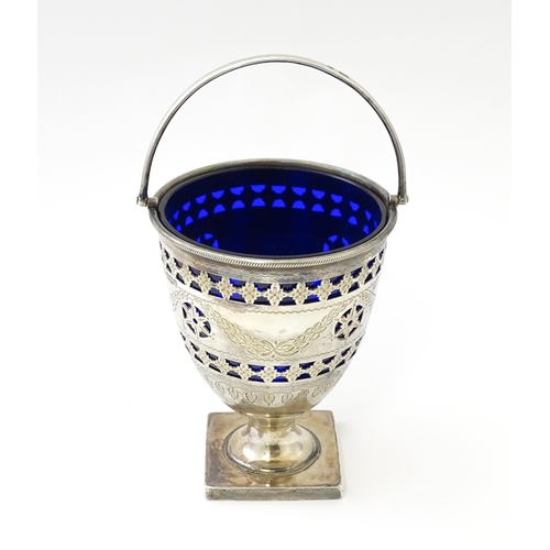 242 - A Victorian silver sugar bowl with swing handle, engraved bright cut decoration and blue glass liner... 