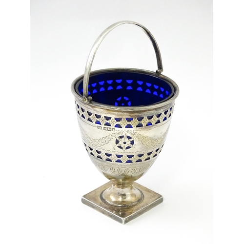 242 - A Victorian silver sugar bowl with swing handle, engraved bright cut decoration and blue glass liner... 